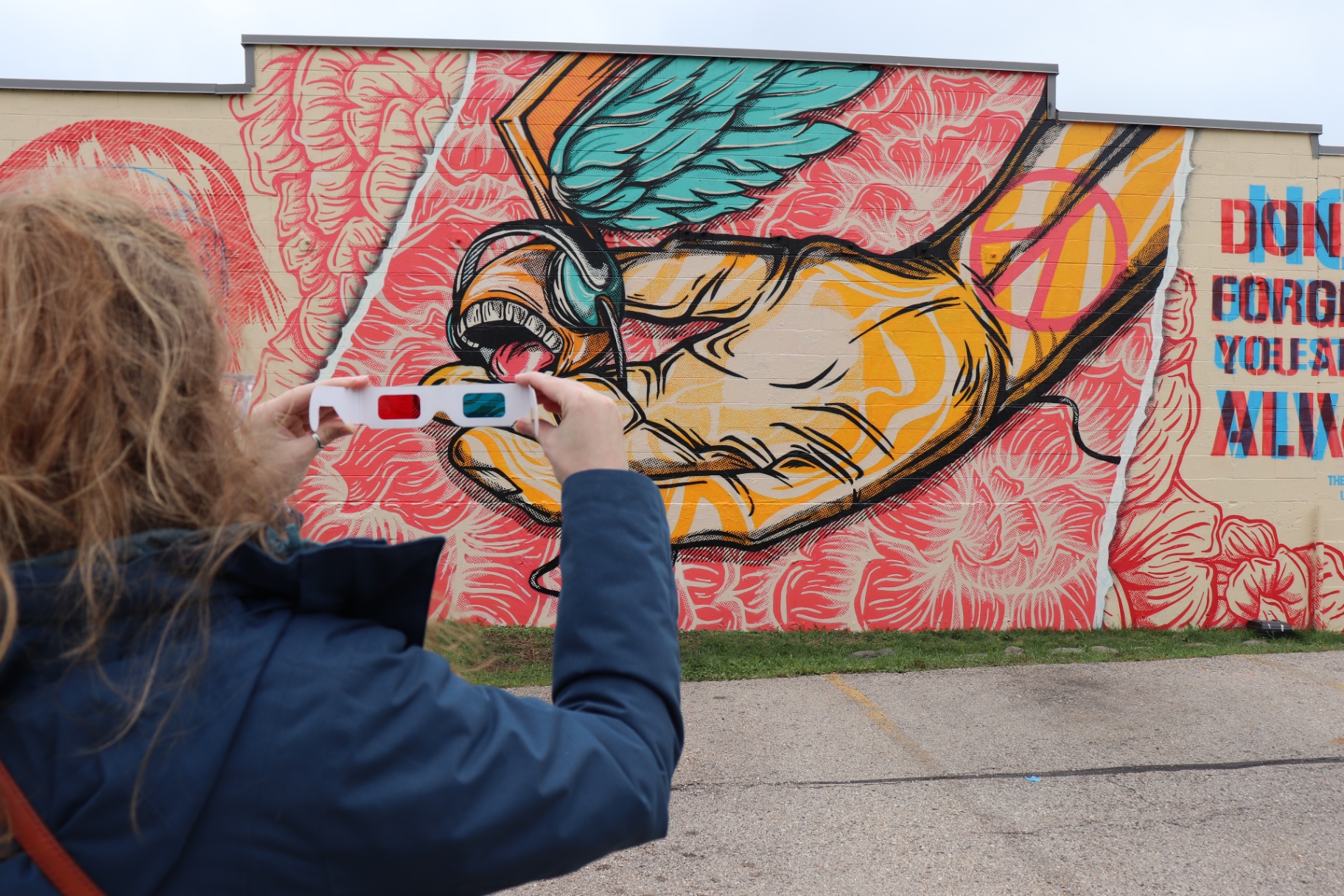 A visitor photographs a colorful destination mural through 3D glasses