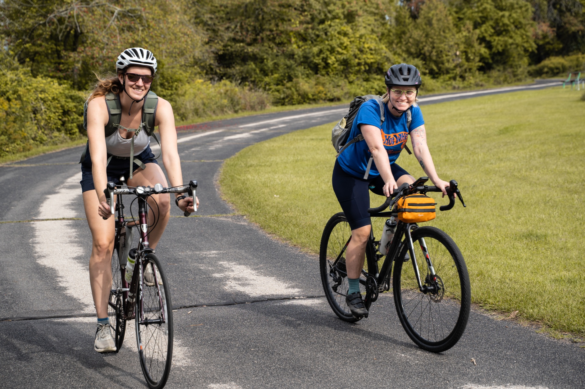 Two cyclists riding side by side on a tree-lined path