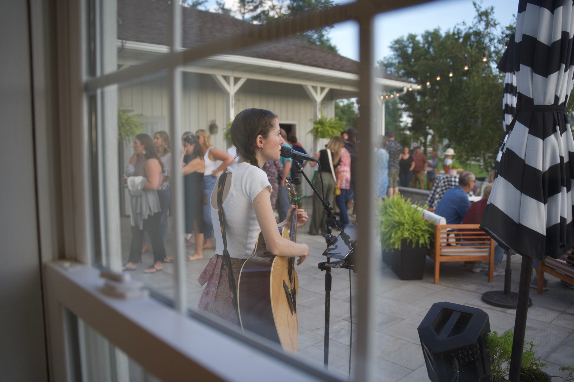 A musician performing live on a patio with a crowd gathered for a local event